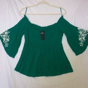 a green, off the shoulder, flowy shirt